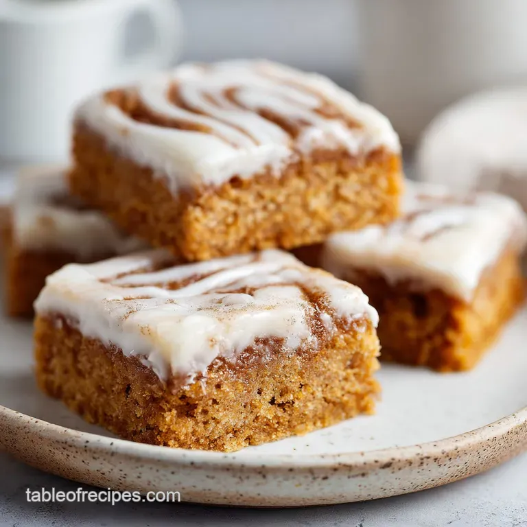 Sliced cinnamon-swirled dessert squares on a white plate, drizzled with creamy icing and paired with fresh berries.